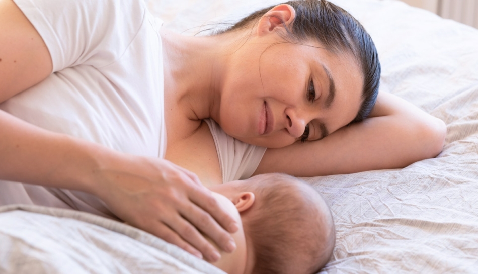 mamma che guarda il suo neonato sdraiata accanto a lui