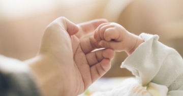 primo piano delle mani di un bambino appena nato e del suo genitore