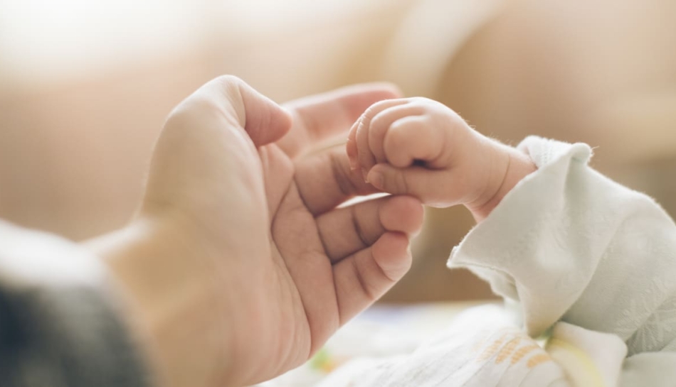 primo piano delle mani di un bambino appena nato e del suo genitore