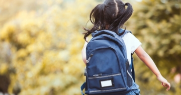 Little girl seen from behind with a backpack on her shoulders