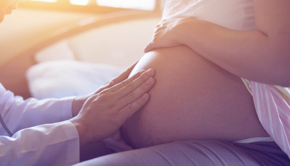 Primo piano sulla pancia di una donna incinta che viene visitata da un medico