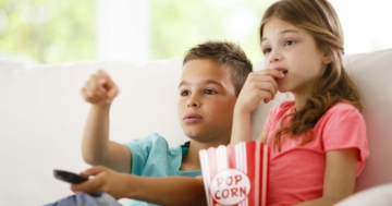 Bambini che guardano la televisione e la pubblicità sul divano