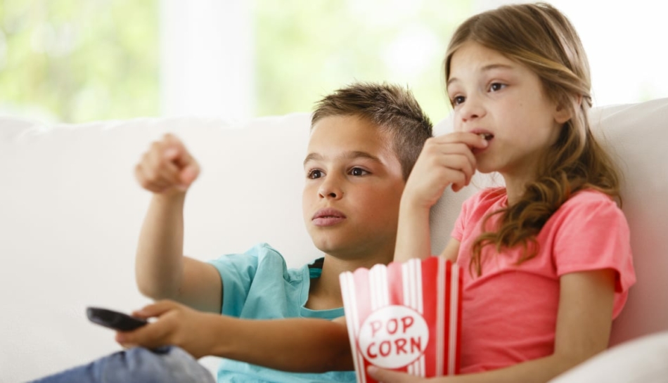 Bambini che guardano la televisione e la pubblicità sul divano