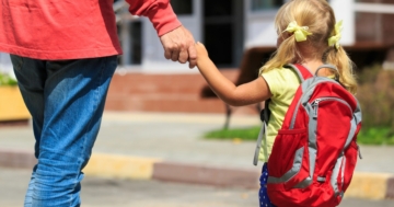 Papà e figlia di spalle davanti alla scuola per cominciare l'ambientamento