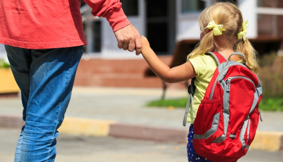 Papà e figlia di spalle davanti alla scuola per cominciare l'ambientamento