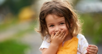 Little girl covering her mouth with her hand