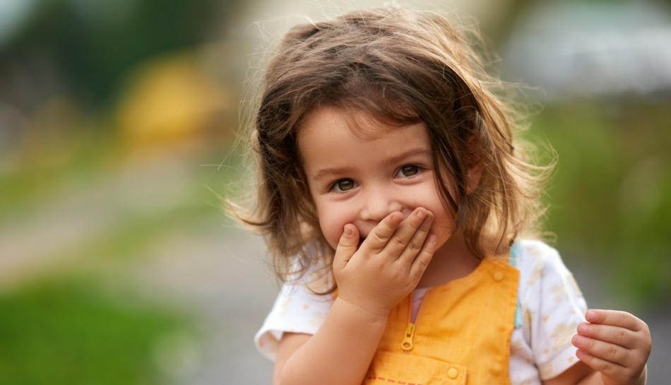 Bambina che si copre la bocca con la mano