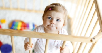 Bambina che sta in piedi dentro un box per giocare