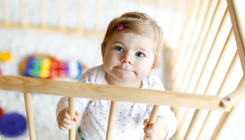 Bambina che sta in piedi dentro un box per giocare