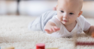 Bambino cerca di raggiungere un oggetto a terra