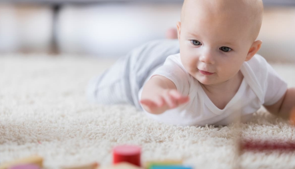 Bambino cerca di raggiungere un oggetto a terra