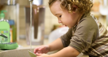 The little girl washes the dishes independently