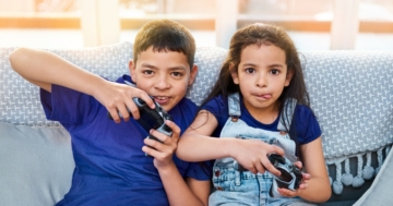 Due bambini sul divano che giocano ai videogiochi