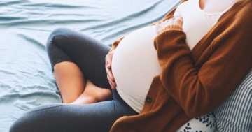 Ventre di una donna incinta seduta sul letto