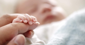 primo piano della mano di un neonato che tiene il dito della mamma
