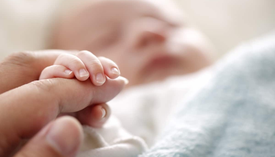 primo piano della mano di un neonato che tiene il dito della mamma