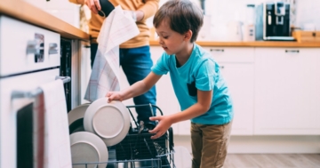 The obedient child helps load the dishwasher