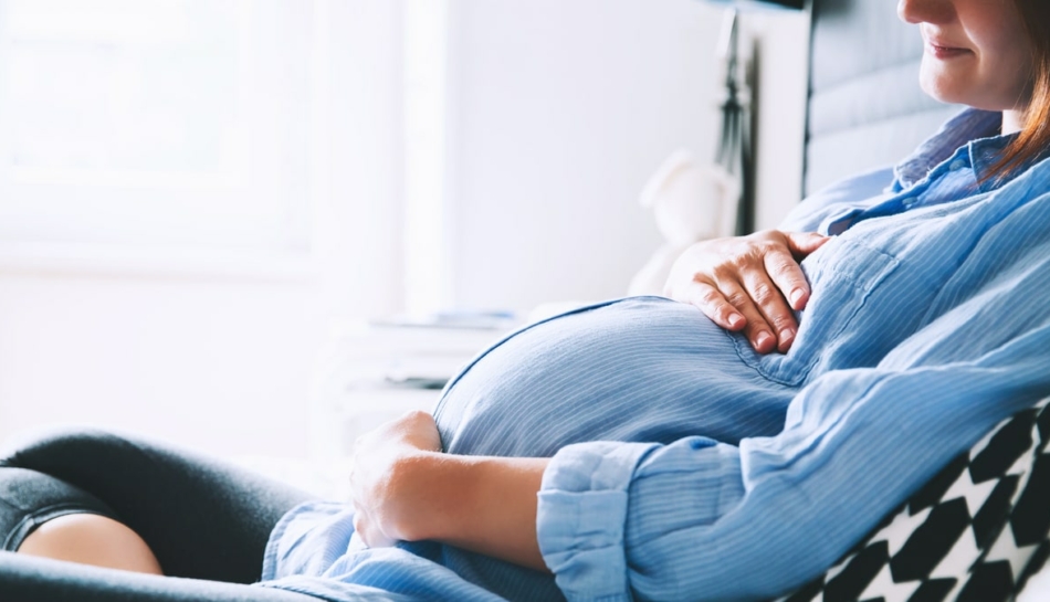 primo piano della pancia di una donna incinta seduta
