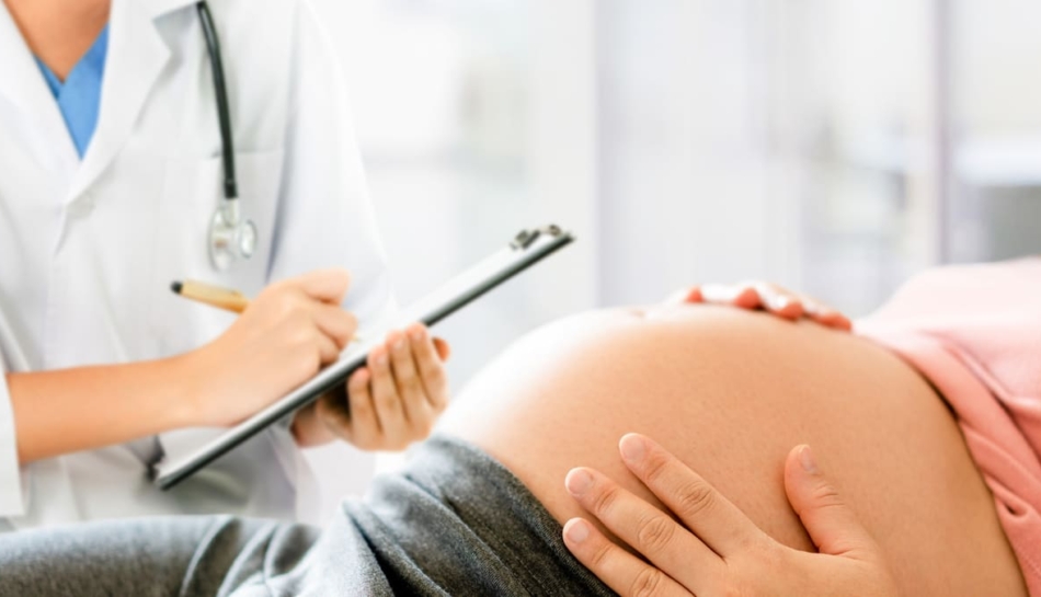 una donna incinta sdraiata parla con il suo medico