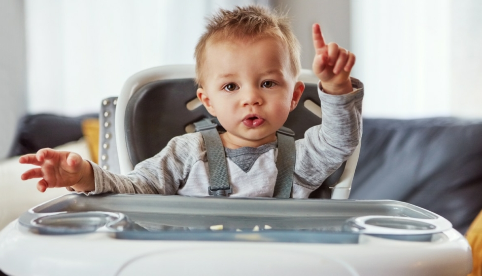 Bambino seduto sul seggiolone fa gesti