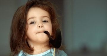 Bambina che finge di fumare con una pipa di carta