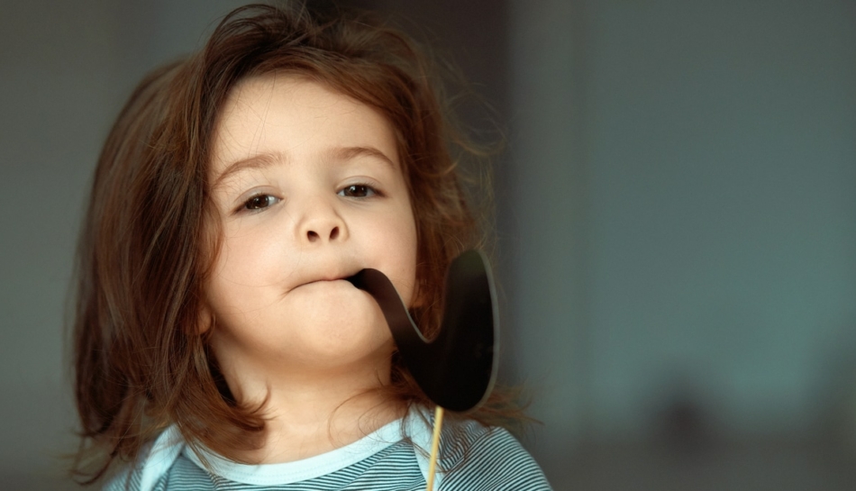 Bambina che finge di fumare con una pipa di carta