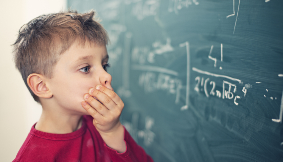 Bambino alla lavagna che risolve un problema di matematica