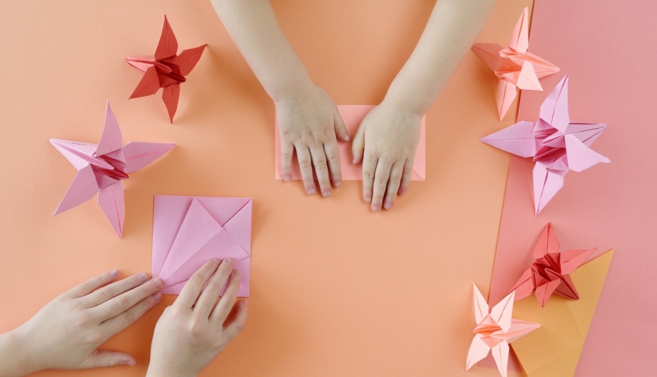 Mani di bambini che realizzano degli origami