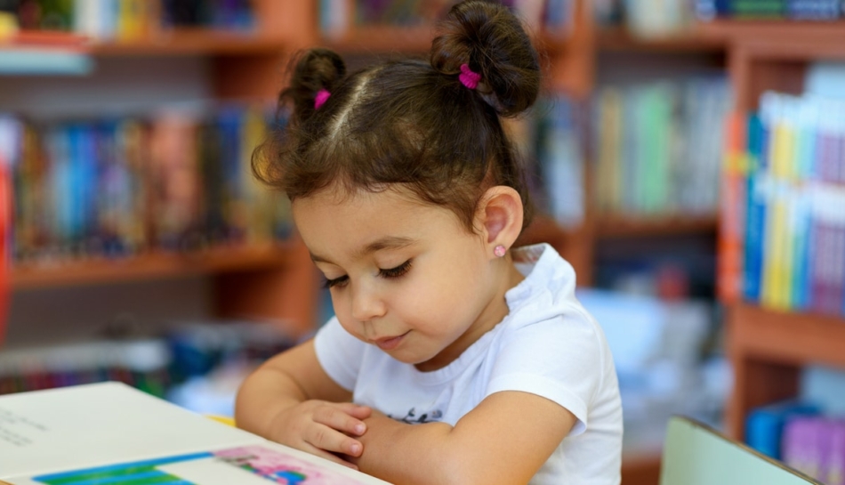 Bambina che legge seduta a un tavolo