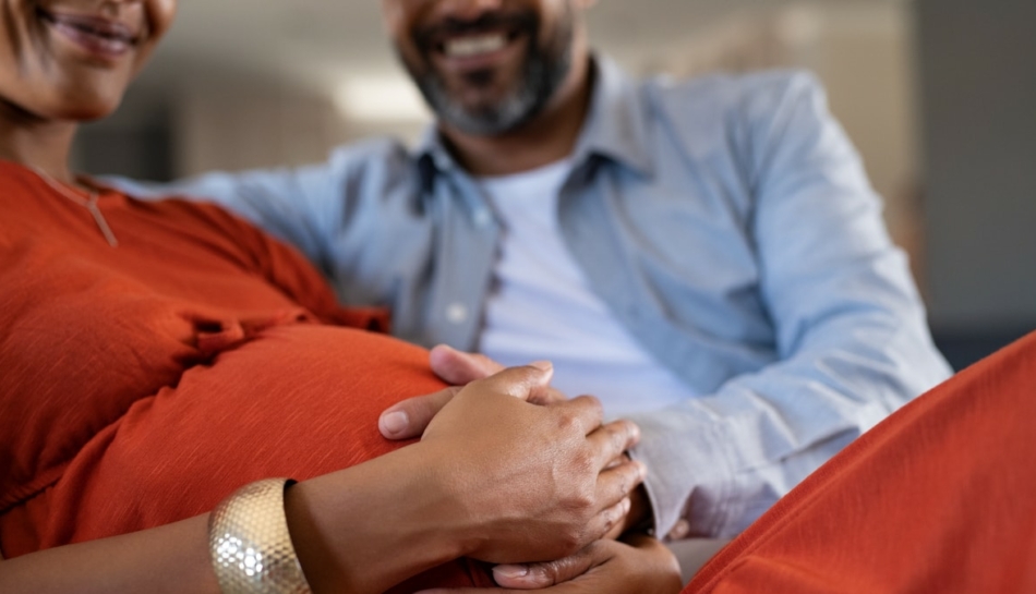 Primo piano delle mani di un papà e una mamma in gravidanza