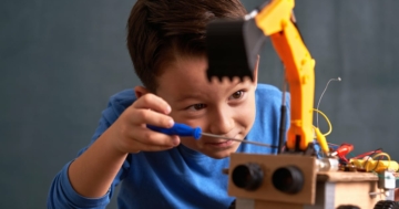 Bambino di circa 6 anni che costruisce un piccolo robot