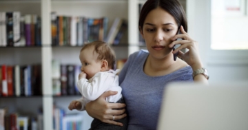 Una mamma tiene in braccio il figlio lattante mentre lavora