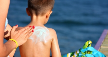 mamma che spalma la crema solare sulla schiena del suo bambino