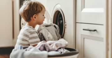 Bambino che si dedica alle faccende domestiche in famiglia, caricando la lavatrice