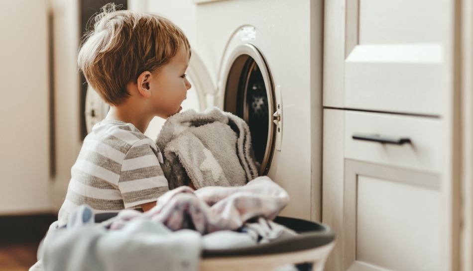 Bambino che si dedica alle faccende domestiche in famiglia, caricando la lavatrice