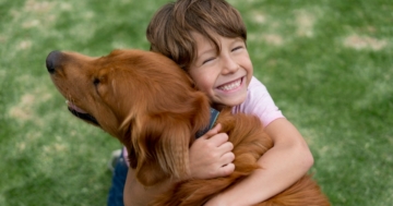 Un bambino abbraccia felice il suo cane