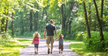 Un papà con i suoi bambini, di schiena, camminano in un ambiente naturale, tutelando la propria salute