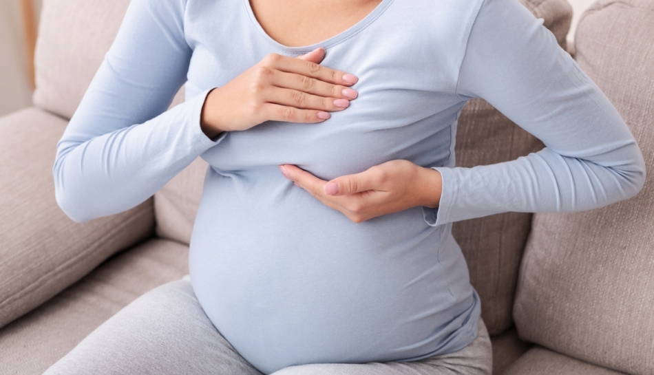 Donna in gravidanza si tasta il seno