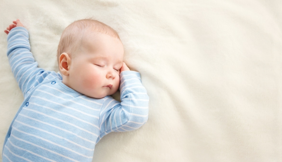 Lattante che dorme a pancia in su, sdraiato su una coperta