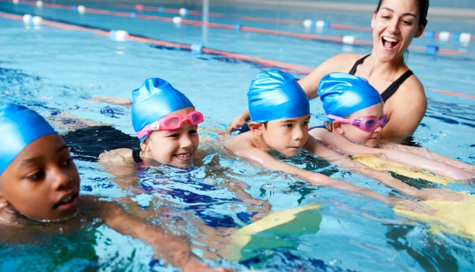 Bambini in piscina durante una lezione di nuoto con la loro insegnante