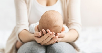 madre tiene neonato facendo attenzione a fontanella cranica