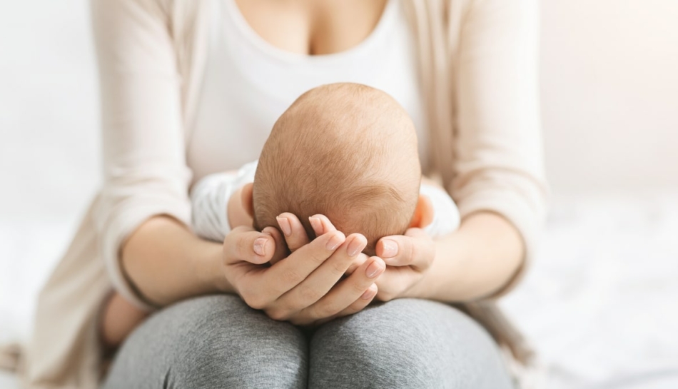 madre tiene neonato facendo attenzione a fontanella cranica