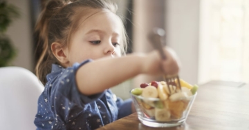 bambina mangia frutta del menù settimanale