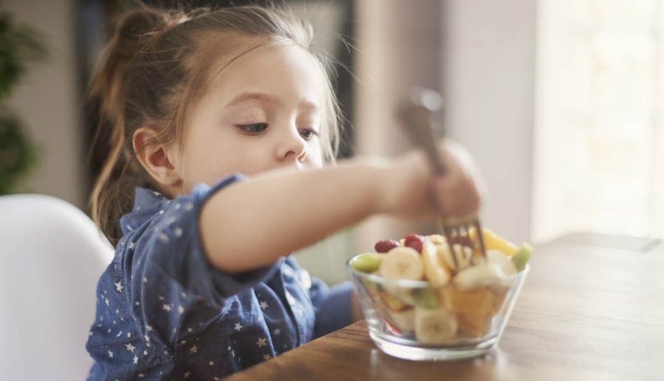 bambina mangia frutta del menù settimanale