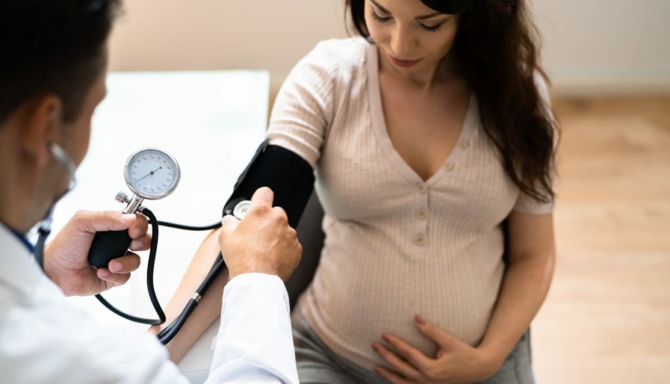 medico misura la pressione a donna in gravidanza