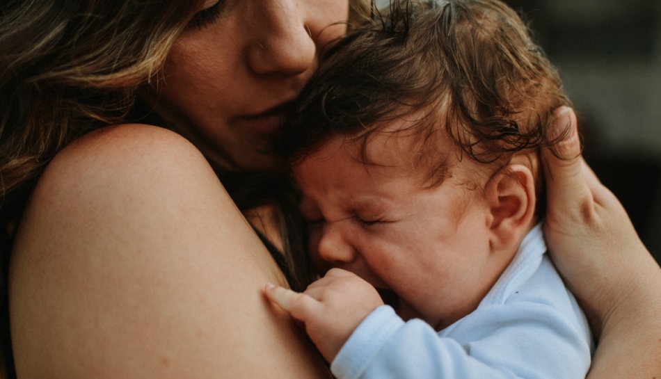 bambino piange in braccio alla mamma per scatti di crescita