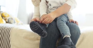 mamma allaccia le scarpe a bambino con disprassia