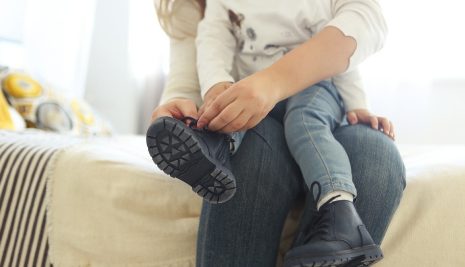 mamma allaccia le scarpe a bambino con disprassia