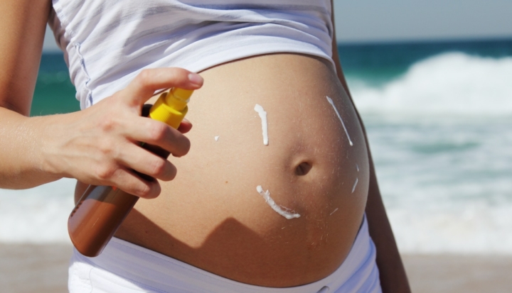 donna in gravidanza mette crema solare sulla pancia