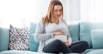 donna in gravidanza con mani su pancia per bruciore di stomaco